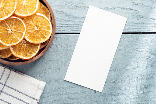 Recipe card with dried orange slices on plate on wood background