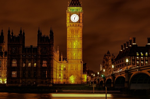 The nighttime view of Big Ben and Parliament with an illuminated bridge in London