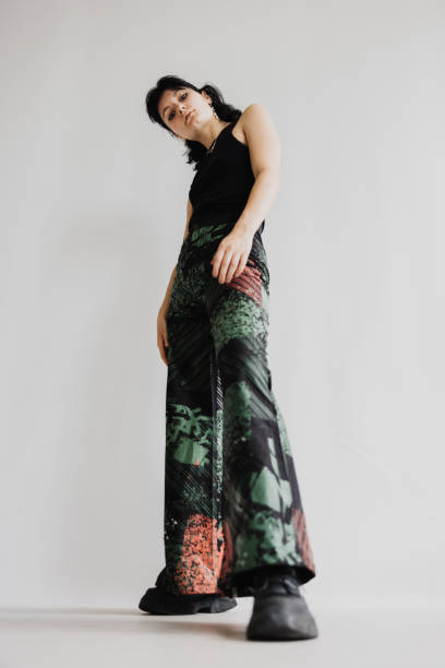 istock Young Adult Looking Down At The Camera While Tilting Her Head Slightly And Wearing Baggy Pants 2068330825