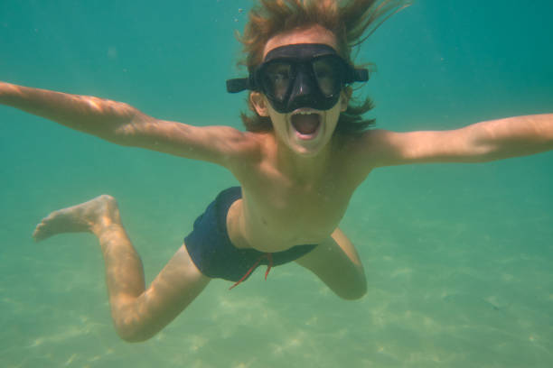 istock Boy with mouth opened swimming underwater 2068383384