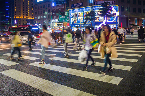 Crowds of shoppers crossing the streets of Myeong-dong overlooked by the neon lights of stores in the heart of Seoul at night, South Korea’s vibrant capital city.