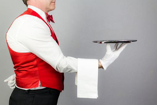 Waiter or Butler in Red Vest Holding Serving Tray