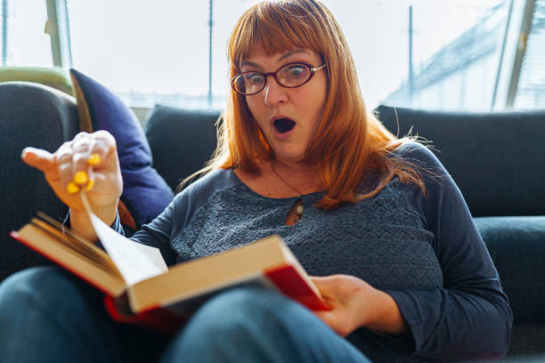 istock Portrait red-haired woman reading novel book 2068441778