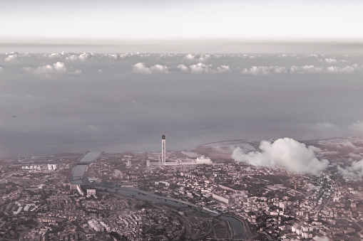 World tallest minaret and third mosque, aerial view from an airplane with clouds over the buildings, the Harrach river and the Mediterranean sea.