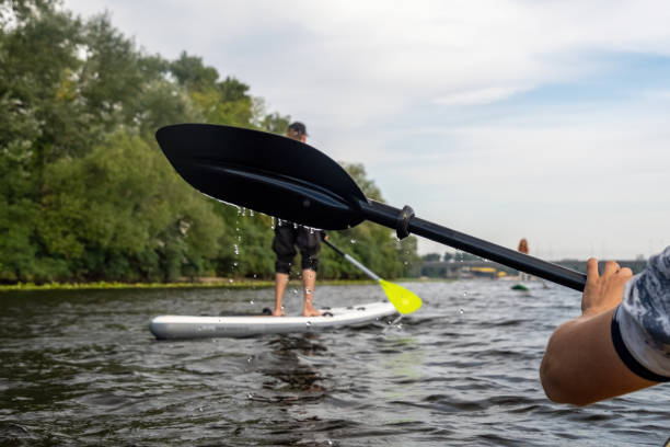 istock Kayaker holds paddle at backdrop of couple gliding on SUP boards 2068460382