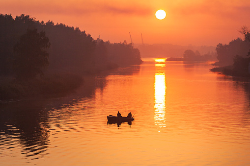 Boat with two fishermen in the river Bullupe at sunrise