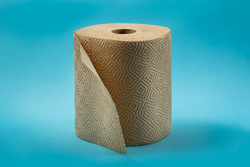 Roll of organic paper towels or brown tissue isolated on blue background.