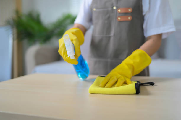 istock A person is cleaning a table with a spray bottle and a yellow cloth 2068499603