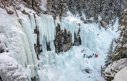 Distant unrecognizable ice climbers on the frozen Upper Falls at Johnston Canyon in Banff National Park, Alberta, Canada