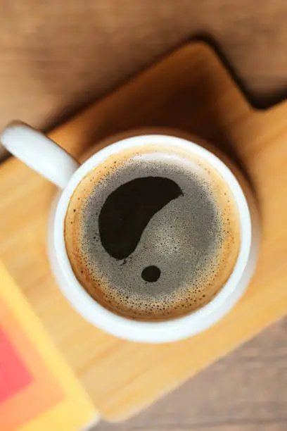 A cup of coffee with a question mark drawn on it, creating curiosity and provoking deep thoughts.