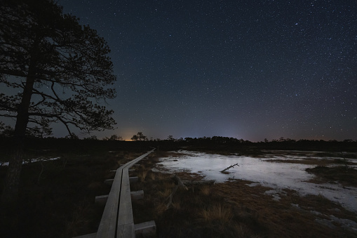Night scene, landscape astrophoto at Seli raba, wooden path for travelers on foot and starry sky. High quality photo