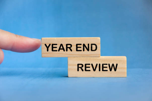 istock Finger pointing Year End Review text on wooden block with blue background. Mid Term budgeting concept 2068562649