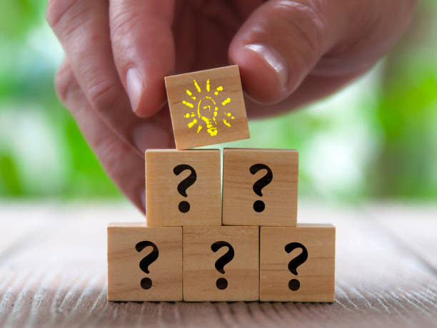 istock Hand holding bulb on wooden cube with stacking question marks.Ideas concepts 2068562653