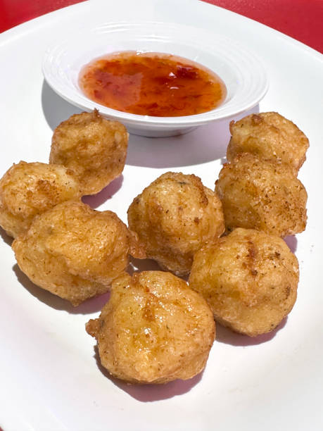 istock Full frame image of white plate containing spicy, deep-fried Chinese pork balls and a dipping bowl of sweet chilli sauce on Chinese restaurant table, red background, elevated view, focus on foreground 2068570013