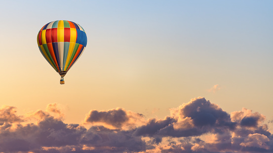 A colorful hot air balloon sails through a deep blue sky.