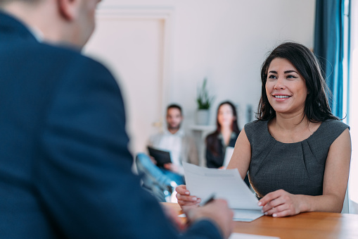 Shot of a male recruiter interview female candidate. Applicant presenting her resume to director while sitting with him at table during job interview.