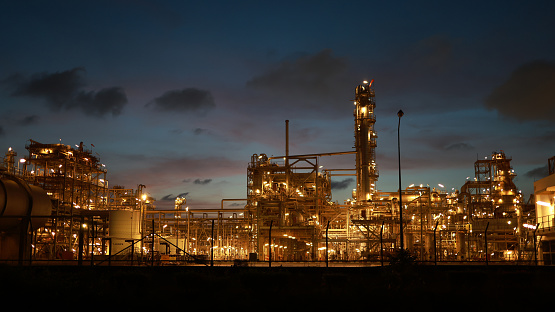A large, modern petrochemical plant at dusk in industrial district near Rotterdam, Netherlands, Benelux, Europe. Distillation towers and other installations are visible against blue sky. 50 megapixel image taken with Canon EOS 5Ds, digital blending technique, long exposure with tripod.