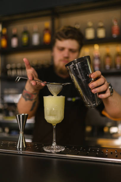 istock Skillful bartender strains cocktail mixture into glass 2068593858