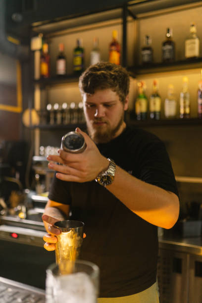 istock Youthful bartender stands near bar counter holding shaker 2068602337