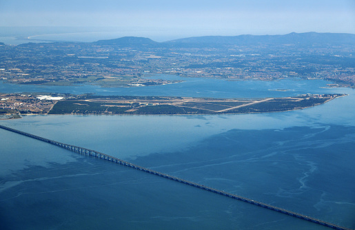 Setubal district, Portugal: aerial view of the Mar da Palha (Sea of Straw) inland sea in the Tagus River estuary in front of Lisbon - in the center of the image is the Portuguese Air Force Air Base #6, below it the east part of the Vasco da Gama Bridge can be seen, above the a large part of the Setubal Peninsula with Moita and Barreiro on the riverbank and the Arrabida mountains on the horizon. On the top left lies the mouth of the River Sando and the Troia peninsula.