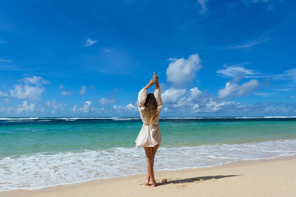istock Young woman walks barefoot on the beach 2068688574