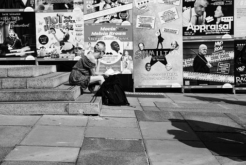Edinburgh, Scotland, August 2023. This is near one of the venues with a young woman sitting in front of some posters for theatre events.