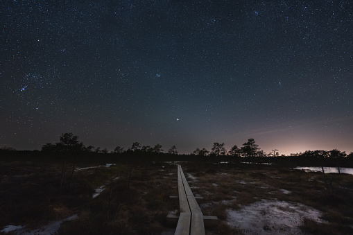 Night scene, landscape astrophoto at Seli raba, wooden path for travelers and starry sky. High quality photo