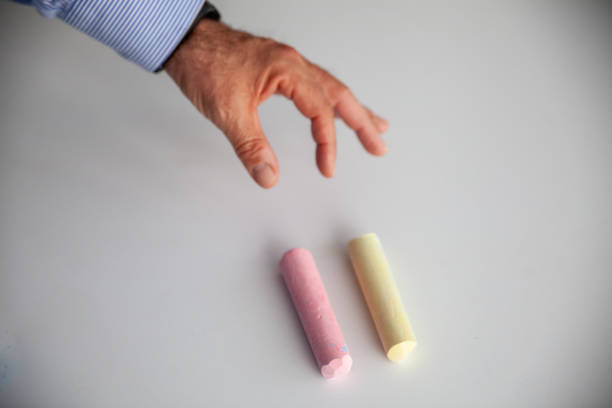 yellow and pink chalks are on white background man hand is choosing horizontal still
