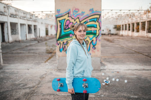 istock A young hipster woman holding a skateboard in her hands while standing near a graffiti wall 2068754590