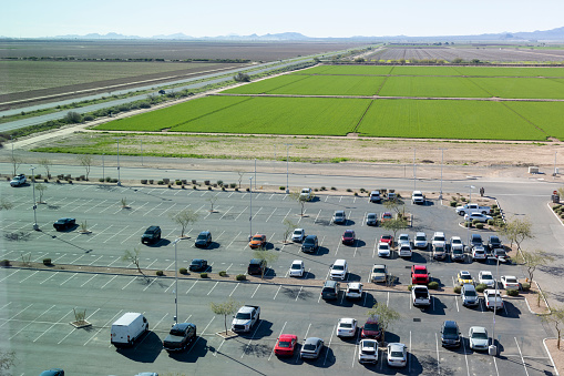 Aerial view of parking area with vehicles and lush agricultural fields in distance