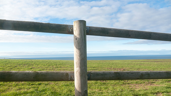 Wooden fence in a green field by the sea in Asturias