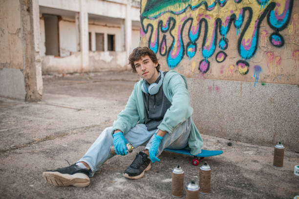 istock A young man looks directly into the camera while sitting in front of a graffiti he has drawn 2068765495