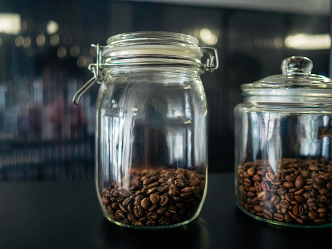 A closeup shot of a glass jar with coffee beans on a table