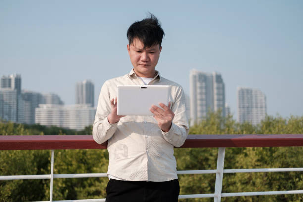 Man using tablet on railing of city street