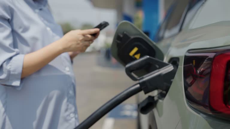 Pregnant woman uses electric car charging station system and modern car technology