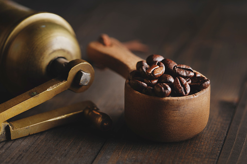 Old copper turkish coffee grinder and rustic wooden spoon with coffee beans