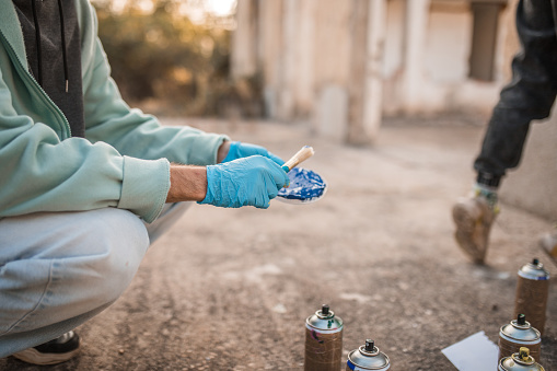 Close-up of the hands of an unrecognizable street artist holding a paint brush