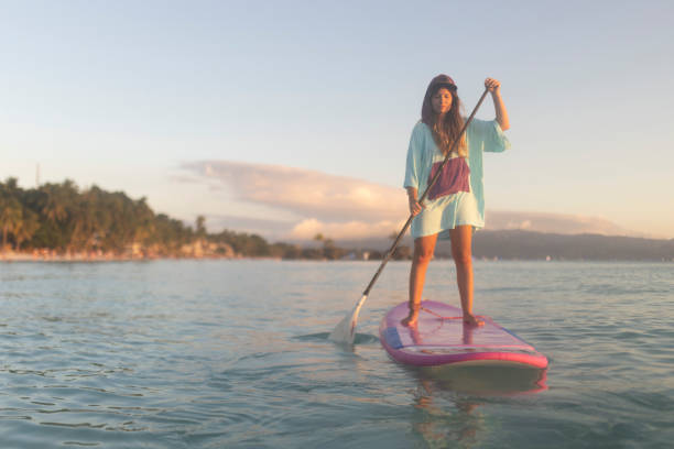 A woman enjoys stand-up paddle boarding, enjoys her vacation and the sea and peace and quiet