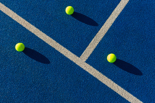 Tennis balls in hard sunlight on synthetic court surface