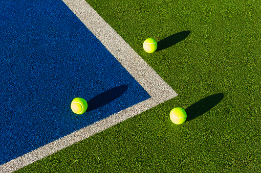 Tennis ball on grass. Bright yellow color sphere on green lawn court, closeup front view, copy space. 3d render