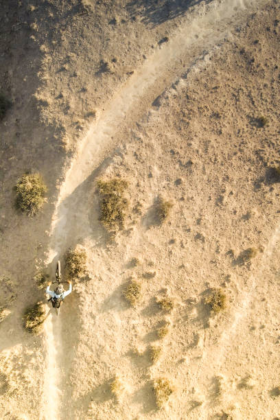 a man mountain bikes within the southwest desert landscape as sunset twilight touches the land.  airborne drone video.