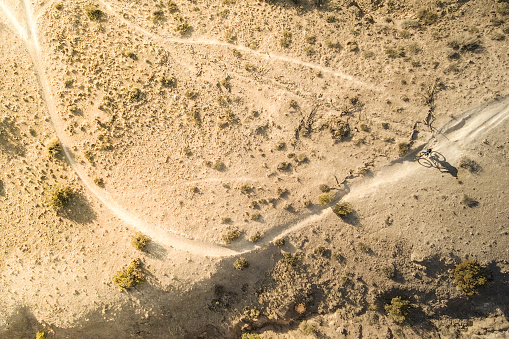 a man mountain bikes within the southwest desert landscape as sunset twilight touches the land.  airborne drone video.
