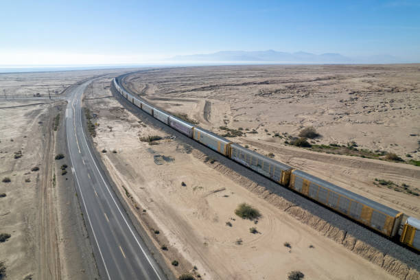 Aerial view of highway and train in parallel on desert