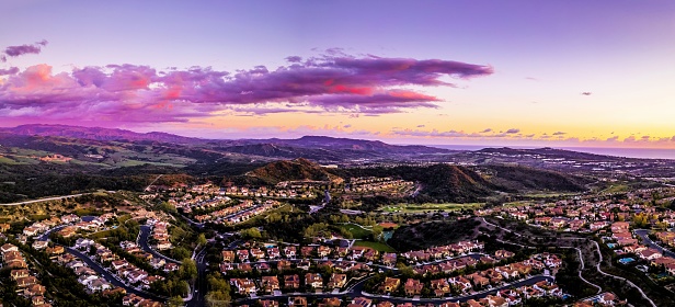 drone photo of large community of single family homes at sunset with colorful clouds