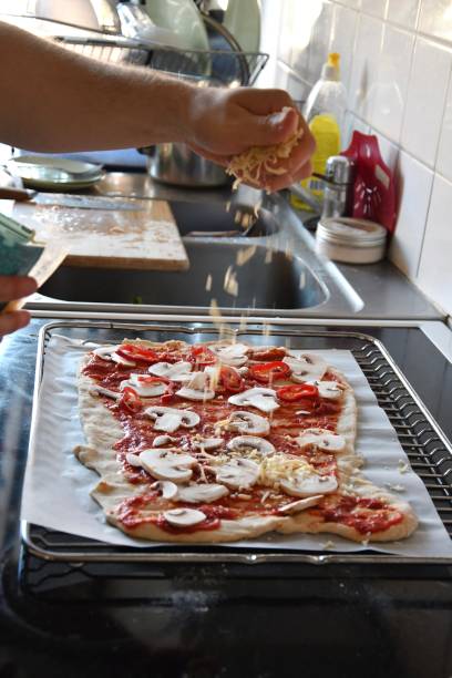 a man putting cheese on pizza, cooking food - pizza sauces chef making imagens e fotografias de stock