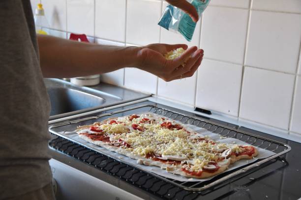 um homem colocando queijo em pizza, cozinhando comida - pizza sauces chef making - fotografias e filmes do acervo