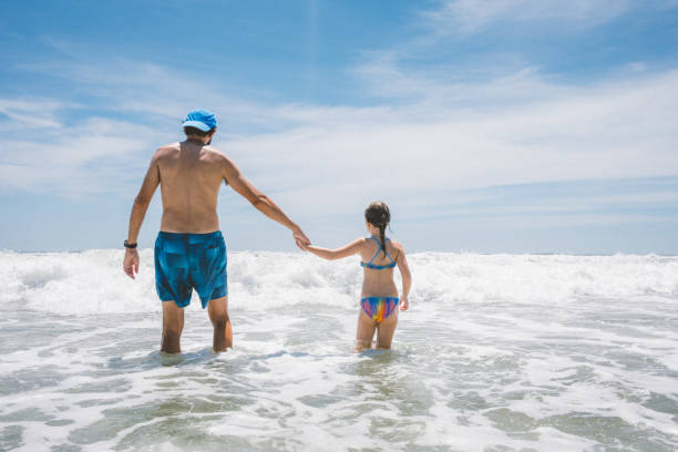 istock Father and daughter jump breaking waves 2068900925