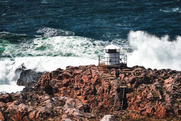 Bay of Pasaia. Waves on the beacons at the mouth of Pasaia with the La Plata lighthouse in the background, Euskadi.