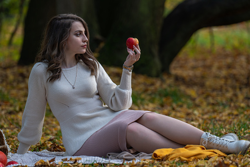 A beautiful girl with dark hair holds an apple in her hand and looks at the fruit. Choice, temptation, temptation, proper nutrition, diet, vegan, organic products.