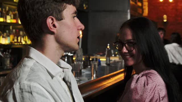 Couple spend time in pub with counter in blurred background